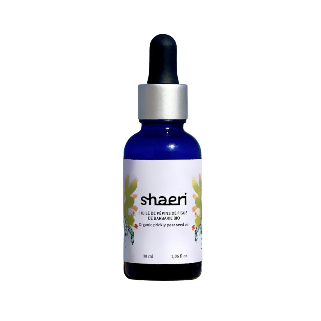 Une bouteille d'huile de pépins de figue de barbarie bio Shaeri, avec un flacon en verre bleu et un compte-gouttes noir.